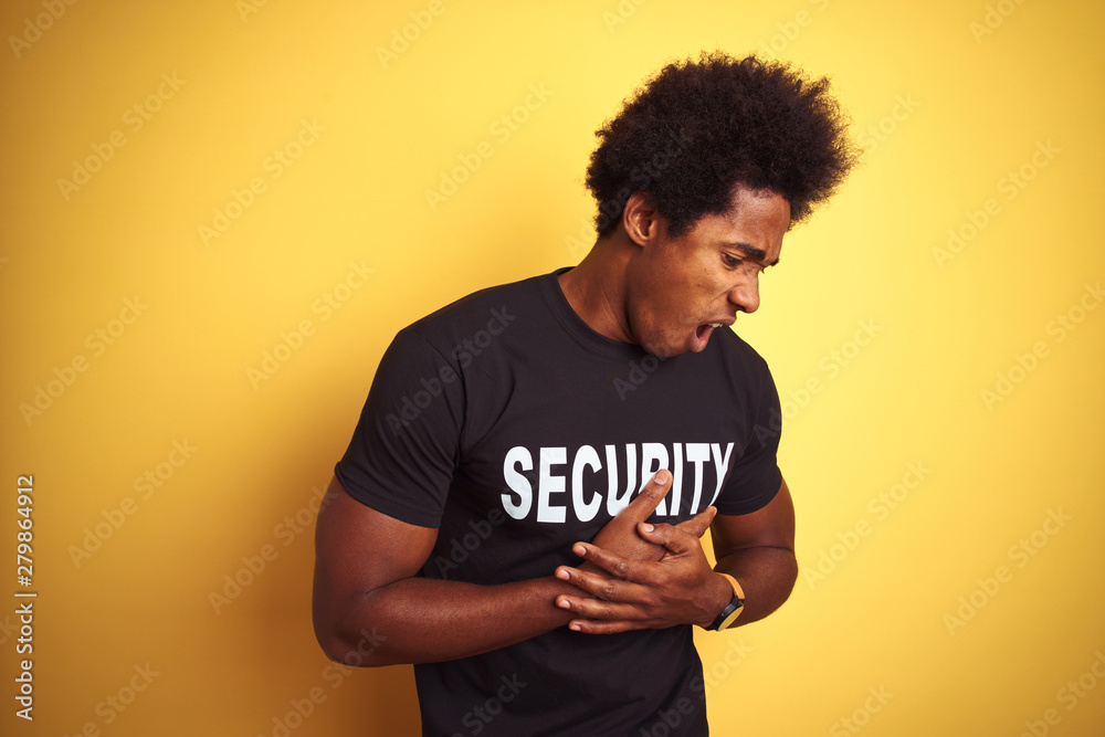 American safeguard man with afro hair wearing security uniform over isolated yellow background with hand on stomach because indigestion, painful illness feeling unwell. Ache concept. American safeguard man with afro hair wearing security uniform over isolated yellow background with hand on stomach because indigestion, painful illness feeling unwell. Ache concept.