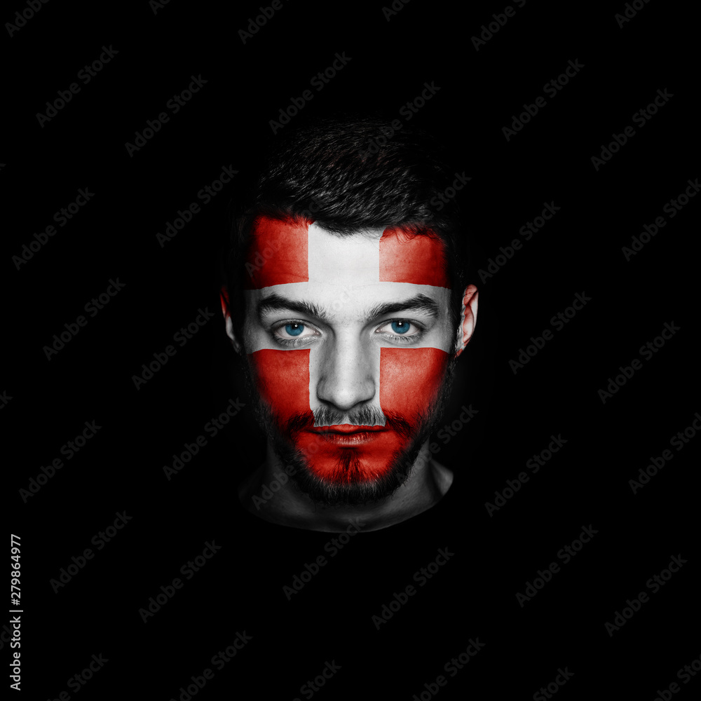 Flag of Switzerland painted on a face of a man on black background.