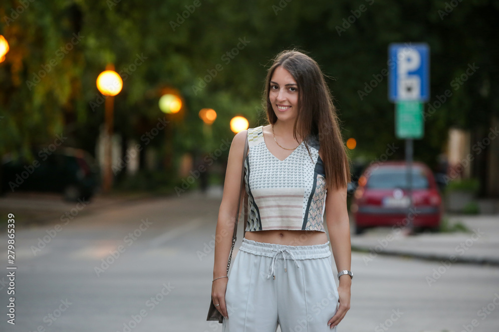 Young fashionable woman posing on the street in the summer evening	