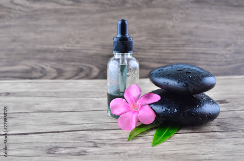 Essence oil and flower with zen stone on wood background