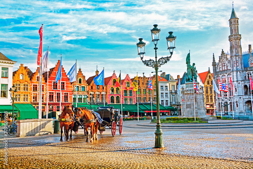 Horse carriages on Grote Markt square in medieval city Brugge at morning, Belgium.