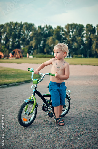 Fototapeta Naklejka Na Ścianę i Meble -  the little boy costs near the bicycle