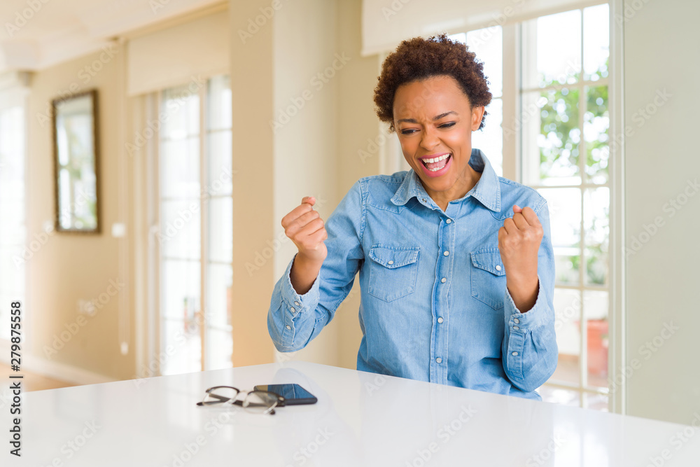 Young beautiful african american woman celebrating surprised and amazed for success with arms raised and open eyes. Winner concept. Young beautiful african american woman celebrating surprised and amazed for success with arms raised and open eyes. Winner concept.