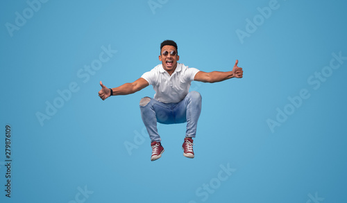 Excited black student jumping and gesturing thumbs up © kegfire