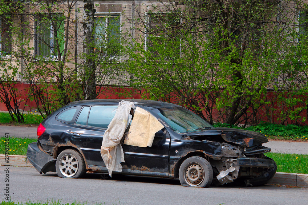 crashed car with a dented hood parked on the side of the road