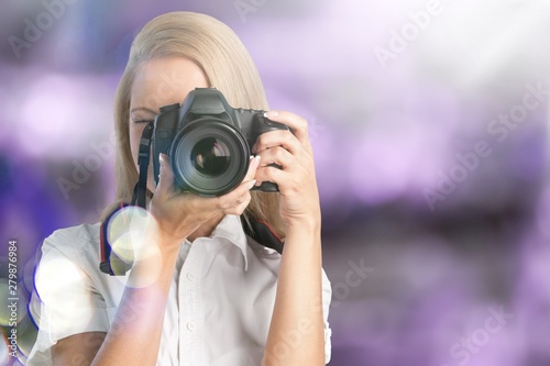 Young woman photographer taking pictures on camera on blurred background