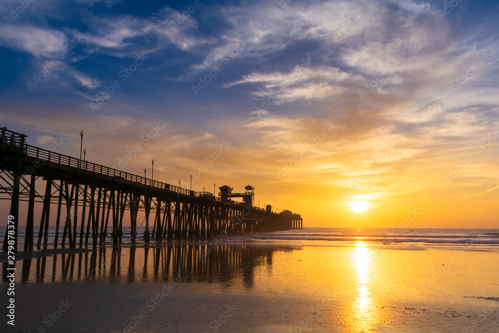 Beautiful sunset sky over the beach and ocean with wooden Oceanside pier - California, USA.