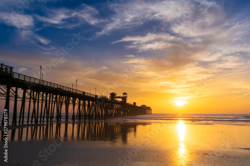 Beautiful sunset sky over the beach and ocean with wooden Oceanside pier - California  USA.