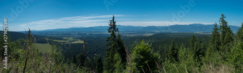View from tatra mountain trail on Baranec to valley with low tatra and blue misty slopes of hills in the distance. Pine trees and coniferous forest hills, blue sky. Tatra mountain in summer, Slovakia. photo