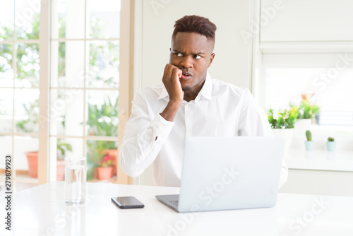 African american business man working using laptop looking stressed and nervous with hands on mouth biting nails. Anxiety problem. © Krakenimages.com