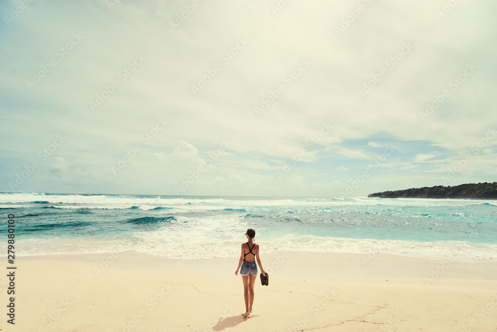 Vacation on the shore. Young woman standing on tropical beach enjoying beautiful view. Vacation on the shore. Young woman standing on tropical beach enjoying beautiful view.