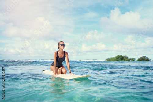Hobby and vacation. Young sexy woman swimming over surfboard in clear blue water at beach, Siargao Island, Philippines.