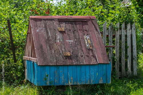 Old wooden well with a house in the countryside. Old village well against the background of an overgrown garden.