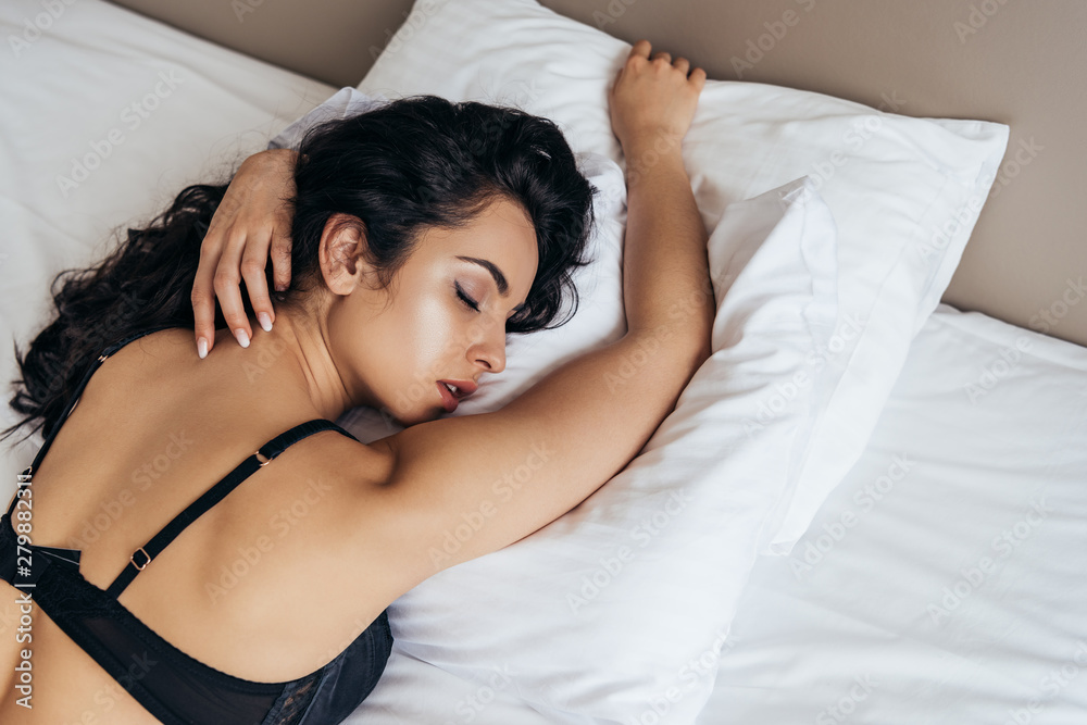 sensual brunette young woman in black bra sleeping on bed Stock Photo