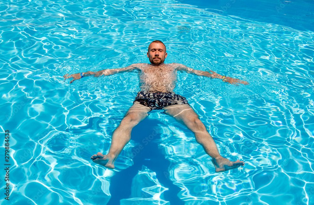 Man swims in the pool on a bright sunny day