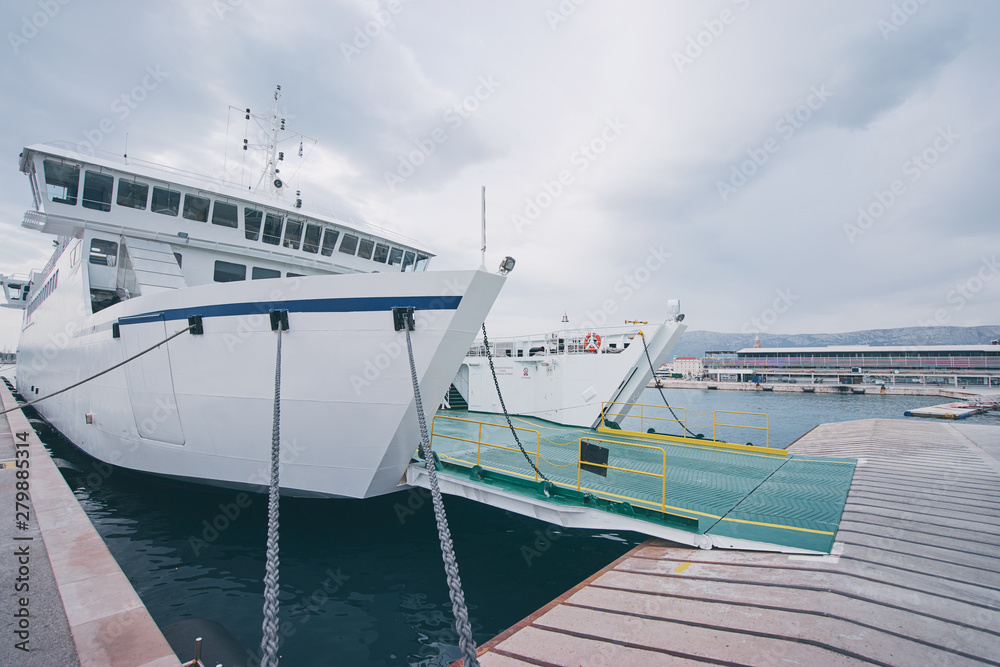 Naklejka premium Ferryboat loading or unloading by a port pier. Concept of transportation and traveling.