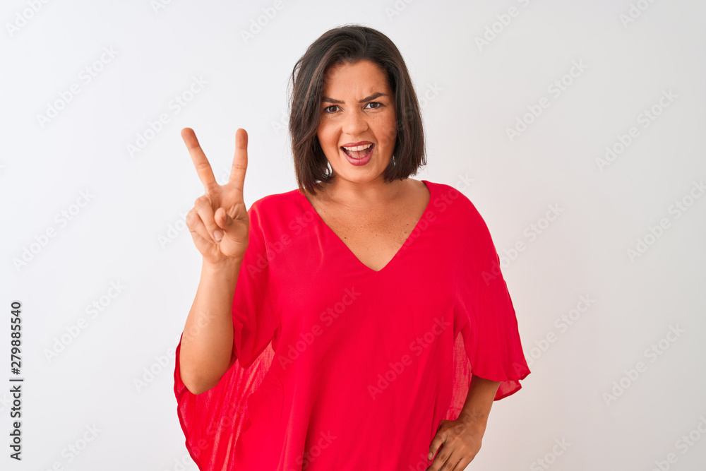 Young beautiful woman wearing red t-shirt standing over isolated white background smiling with happy face winking at the camera doing victory sign. Number two. Young beautiful woman wearing red t-shirt standing over isolated white background smiling with happy face winking at the camera doing victory sign. Number two.