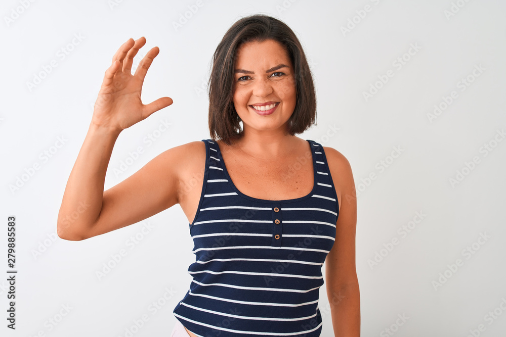 Young beautiful woman wearing blue striped t-shirt standing over isolated white background smiling and confident gesturing with hand doing small size sign with fingers looking and the camera. Young beautiful woman wearing blue striped t-shirt standing over isolated white background smiling and confident gesturing with hand doing small size sign with fingers looking and the camera.