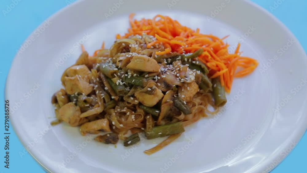 Thai rice noodle dish with chicken vegetables and sesame seeds in Pad Thai sauce. Rotation in a circle