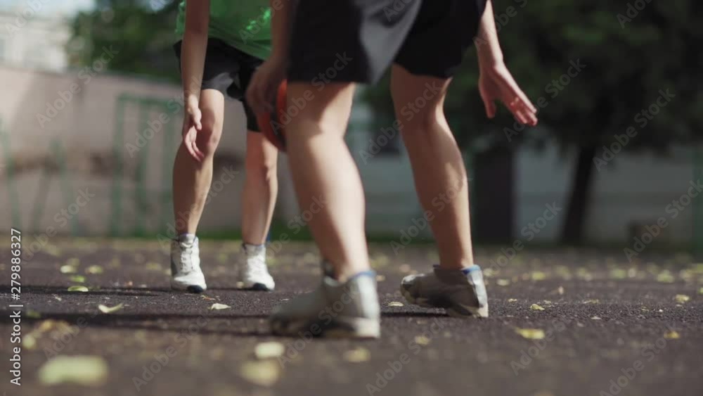 Low angle view of two unrecognizable female athletes playing basketball on outdoor urban court in slow motion. Girl handling ball skillfully Low angle view of two unrecognizable female athletes playing basketball on outdoor urban court in slow motion. Girl handling ball skillfully