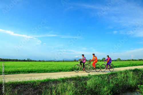 happy young local boy riding old bicycle at paddy field