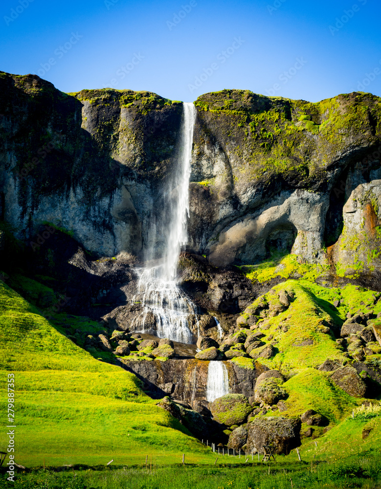 Fototapeta premium Waterfall in green mountain landscape in Iceland
