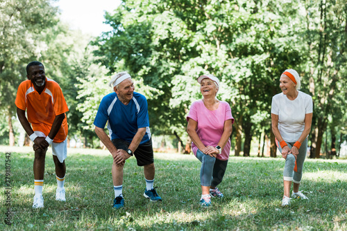 cheerful senior and multicultural people doing stretching exercise on grass