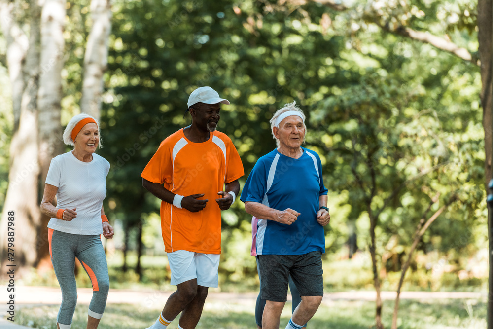 happy multicultural senior men and retired woman running in park