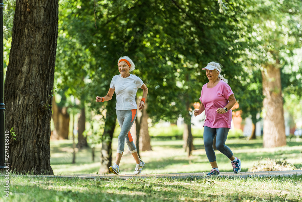 selective focus cheerful senior women in sportswear jogging in park