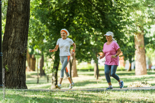 selective focus cheerful senior women in sportswear jogging in park