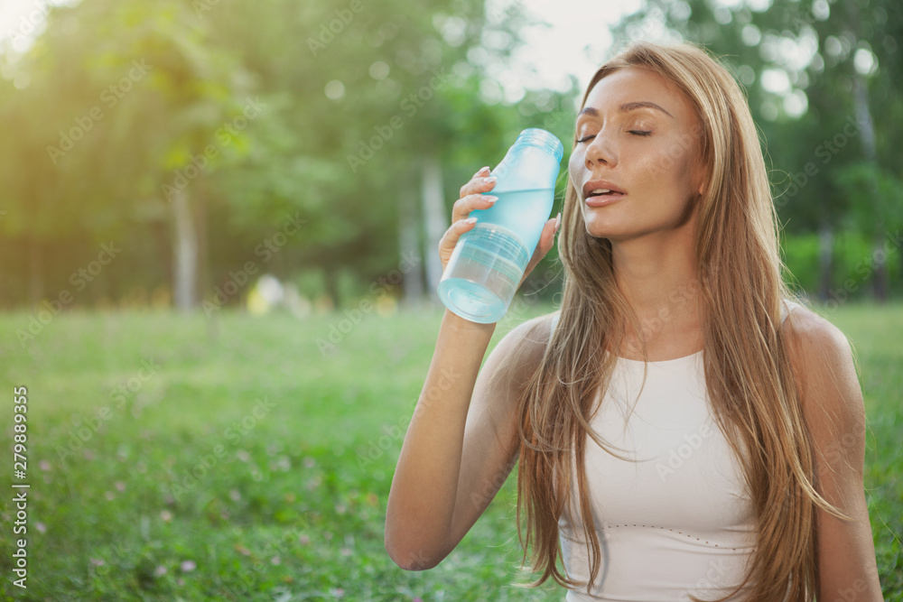 Beautiful red haired woman drinking fresh cool water after working out in the park. Charming sportswoman enjoying drinking water with her eyes closed, copy space Beautiful red haired woman drinking fresh cool water after working out in the park. Charming sportswoman enjoying drinking water with her eyes closed, copy space