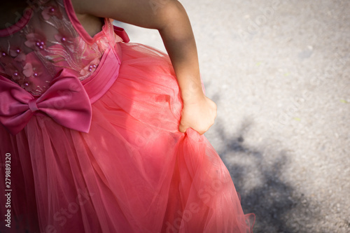 Close-up of part of a little girl with a coral-dress princess dress. Shallow depth of focus.