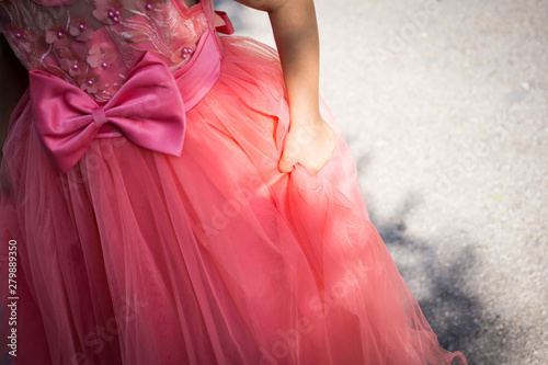 Close-up of part of a little girl with a coral-dress princess dress. Shallow depth of focus.