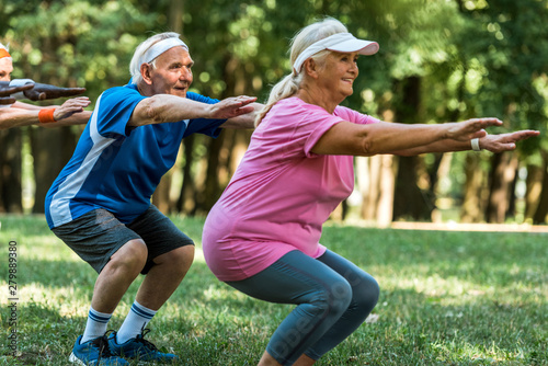 happy multicultural retired people doing sit ups on grass