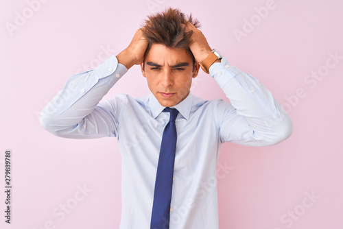 Young handsome businessman wearing shirt and tie standing over isolated pink background suffering from headache desperate and stressed because pain and migraine. Hands on head.