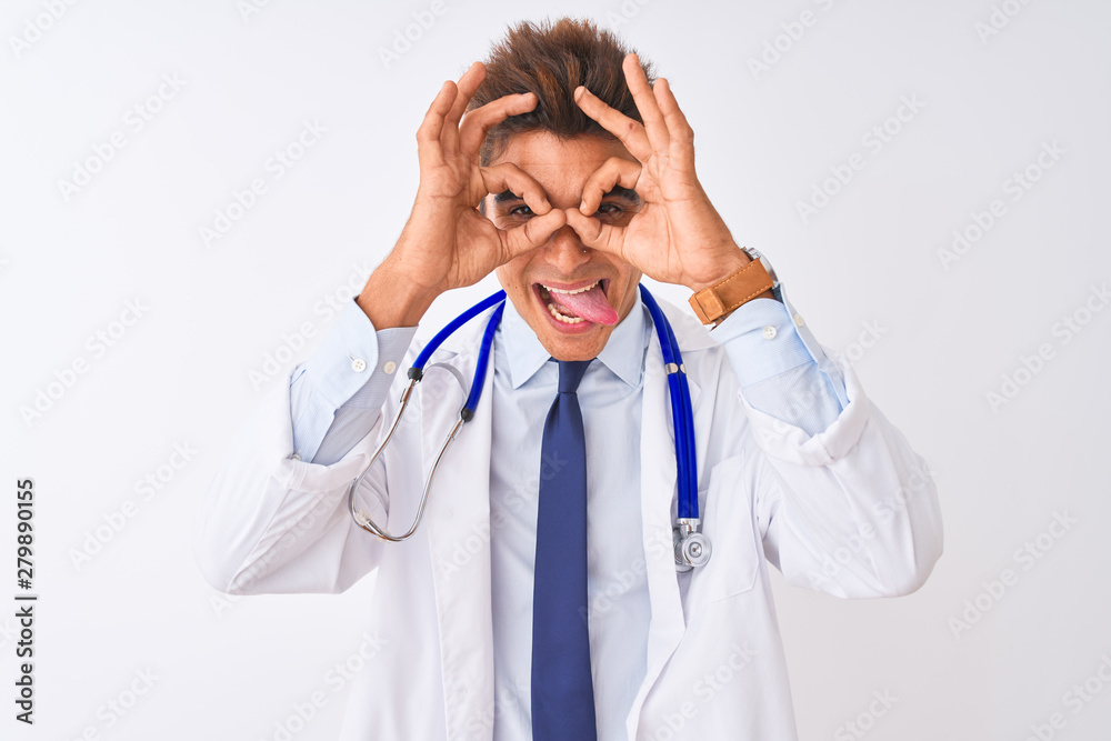 Young handsome doctor man wearing stethoscope over isolated white background doing ok gesture like binoculars sticking tongue out, eyes looking through fingers. Crazy expression. Young handsome doctor man wearing stethoscope over isolated white background doing ok gesture like binoculars sticking tongue out, eyes looking through fingers. Crazy expression.