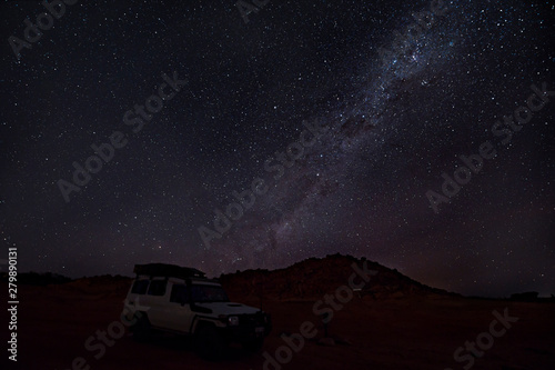Cloudless starlit night sky with Milky Way and bright stars with a 4WD vehicle in front as panorama view for wallpaper and copy space photo