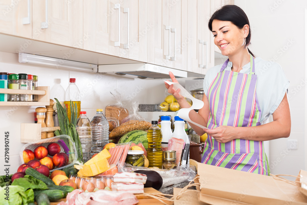 Woman is standing with check and satisfied of the prices of food at home.