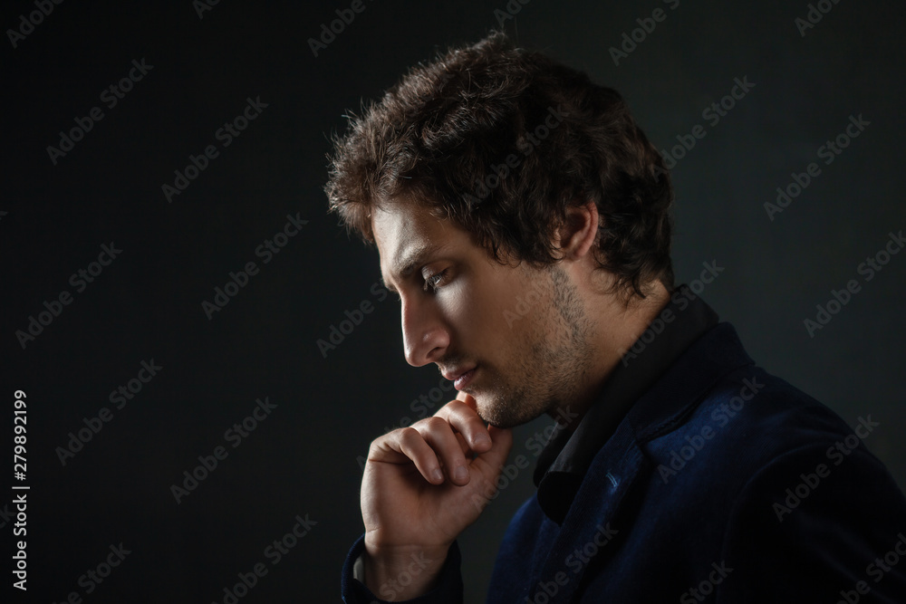 A young brunet male is holding his chin thoughtfully, pointing to the side. A young brunet male is holding his chin thoughtfully, pointing to the side.