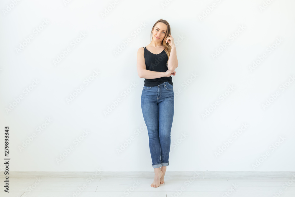 Style, people concept - young woman in jeans and black shirt standing over the white background with copy space Style, people concept - young woman in jeans and black shirt standing over the white background with copy space