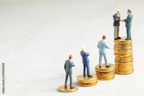 Businessmen shake hands as a symbol of a successful profitable transaction. Businessmen on a stack of gold coins with steps as a symbol of success or successful investments