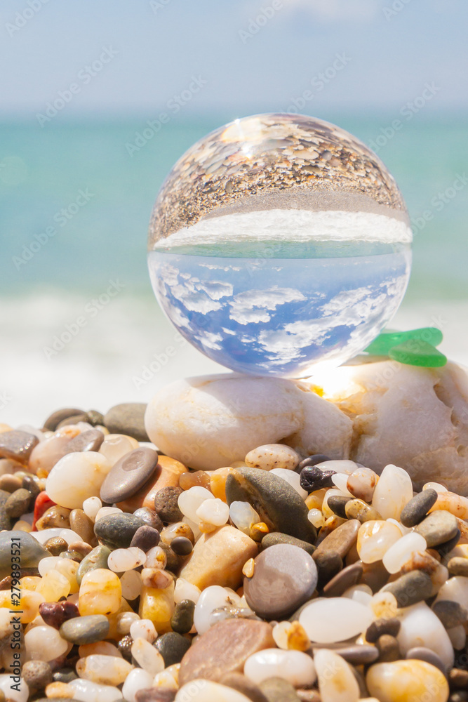 Glass round ball on the beach reflects the sea in summer Glass round ball on the beach reflects the sea in summer