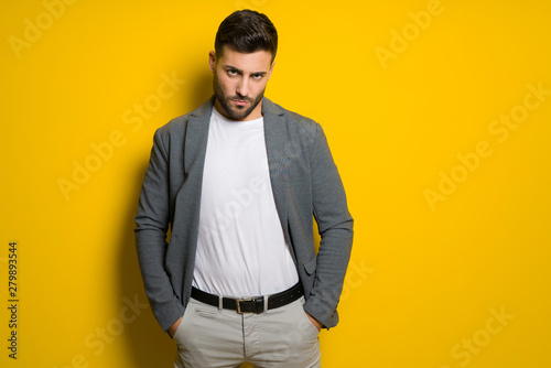 Young handsome man possing and modeling over yellow isolated background