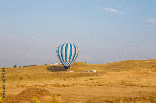 one striped hot balloon stand on the ground and unloads tourists