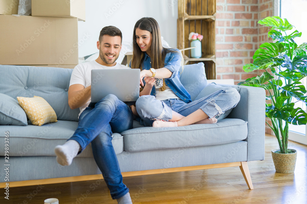 Young couple moving to a new home relaxing sitting on the sofa using computer laptop, smiling happy for moving to new apartment Young couple moving to a new home relaxing sitting on the sofa using computer laptop, smiling happy for moving to new apartment