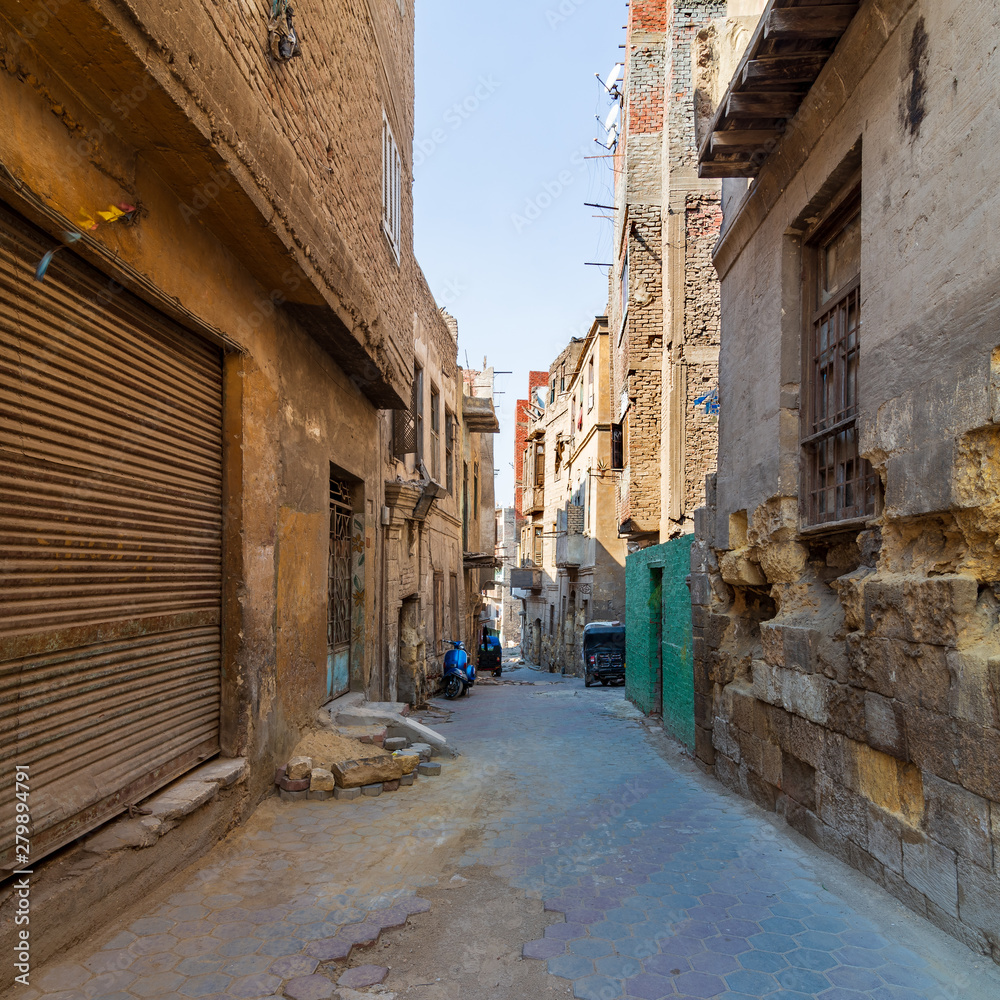 Aged houses with crumbling walls located on narrow abandoned street on