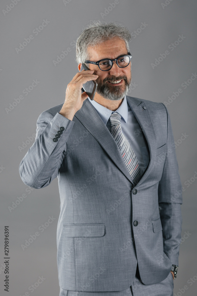 senior businessman using cellphone on gray background senior businessman using cellphone on gray background