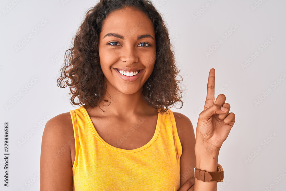 Young brazilian woman wearing t-shirt standing over isolated white background very happy pointing with hand and finger to the side Young brazilian woman wearing t-shirt standing over isolated white background very happy pointing with hand and finger to the side