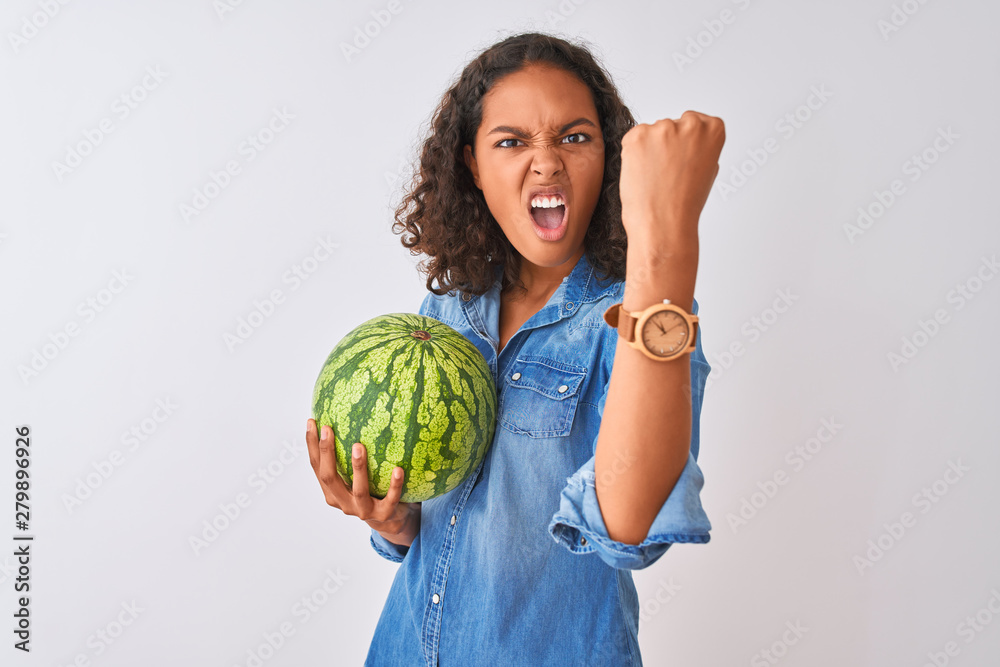 Young brazilian woman holding watermelon standing over isolated white background annoyed and frustrated shouting with anger, crazy and yelling with raised hand, anger concept Young brazilian woman holding watermelon standing over isolated white background annoyed and frustrated shouting with anger, crazy and yelling with raised hand, anger concept