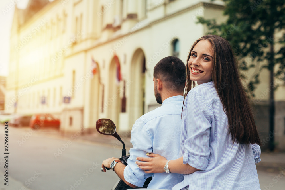 Happy couple on scooter driving outdoor in the city Happy couple on scooter driving outdoor in the city